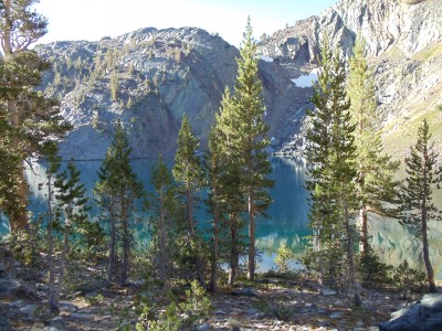 Teal-blue Ruby Lake, ringed by cliffs and a gently sloping trail through trees